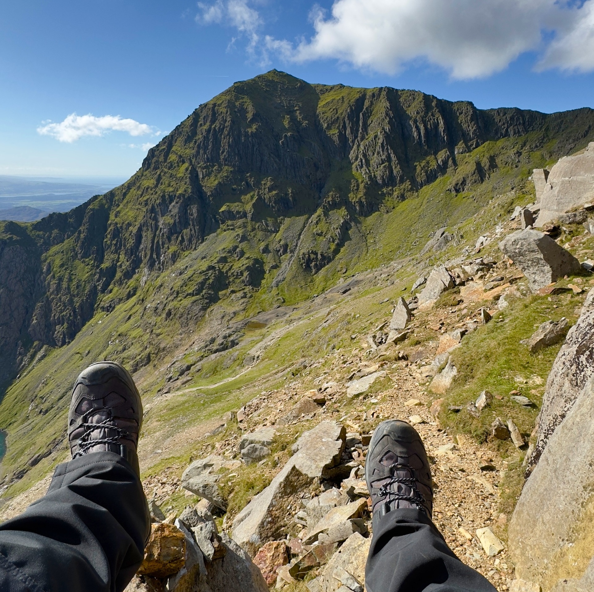 Mark seated on a rock with boots in frame, Snowdon filling the background